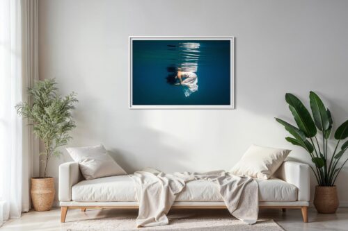 Framed underwater fine art photography print displayed on the wall above a sofa in a contemporary living room setting.