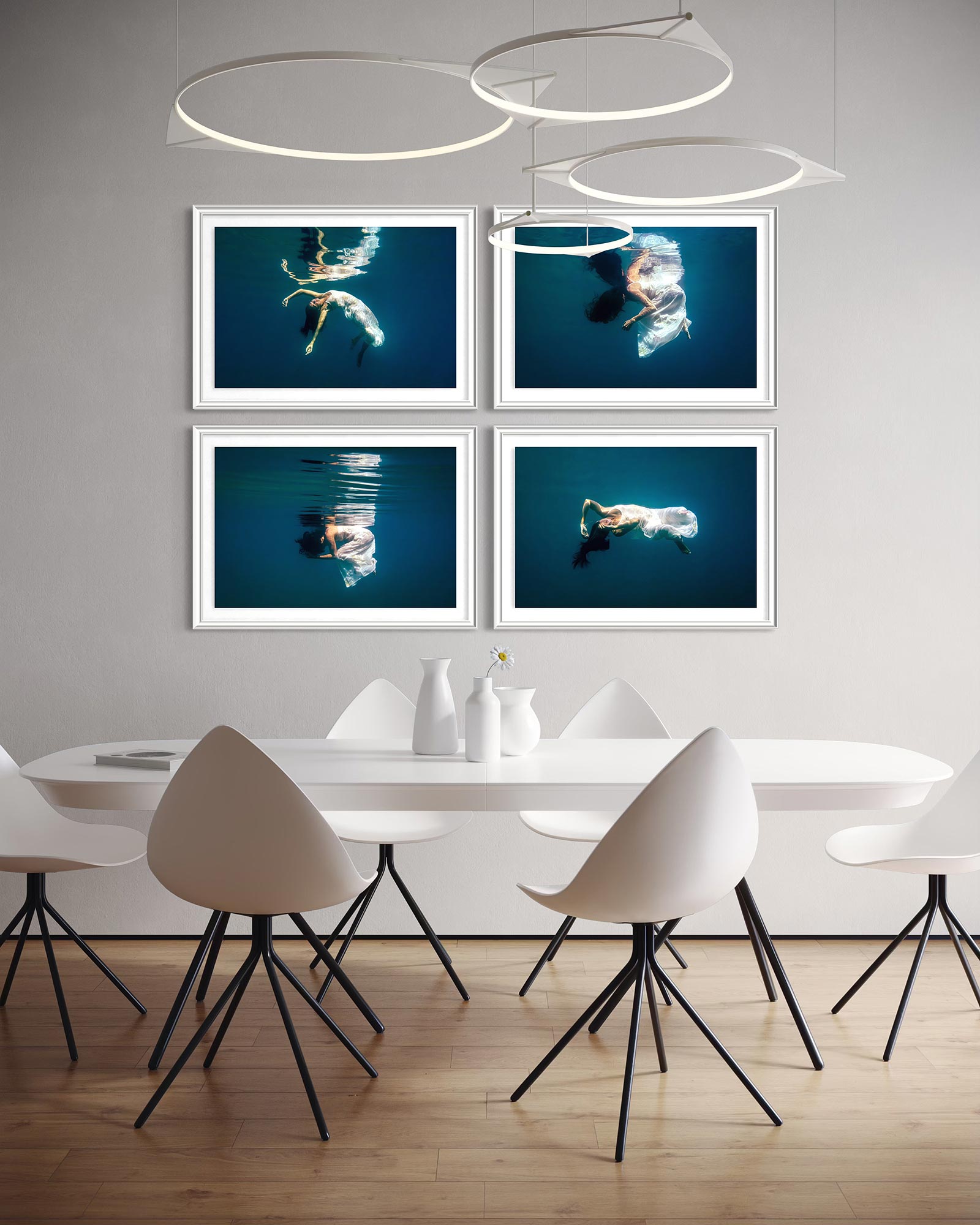 A quadriptych of fine art underwater portraits photo prints displayed in four frames in a modern, bright, minimalistic kitchen above the table.
