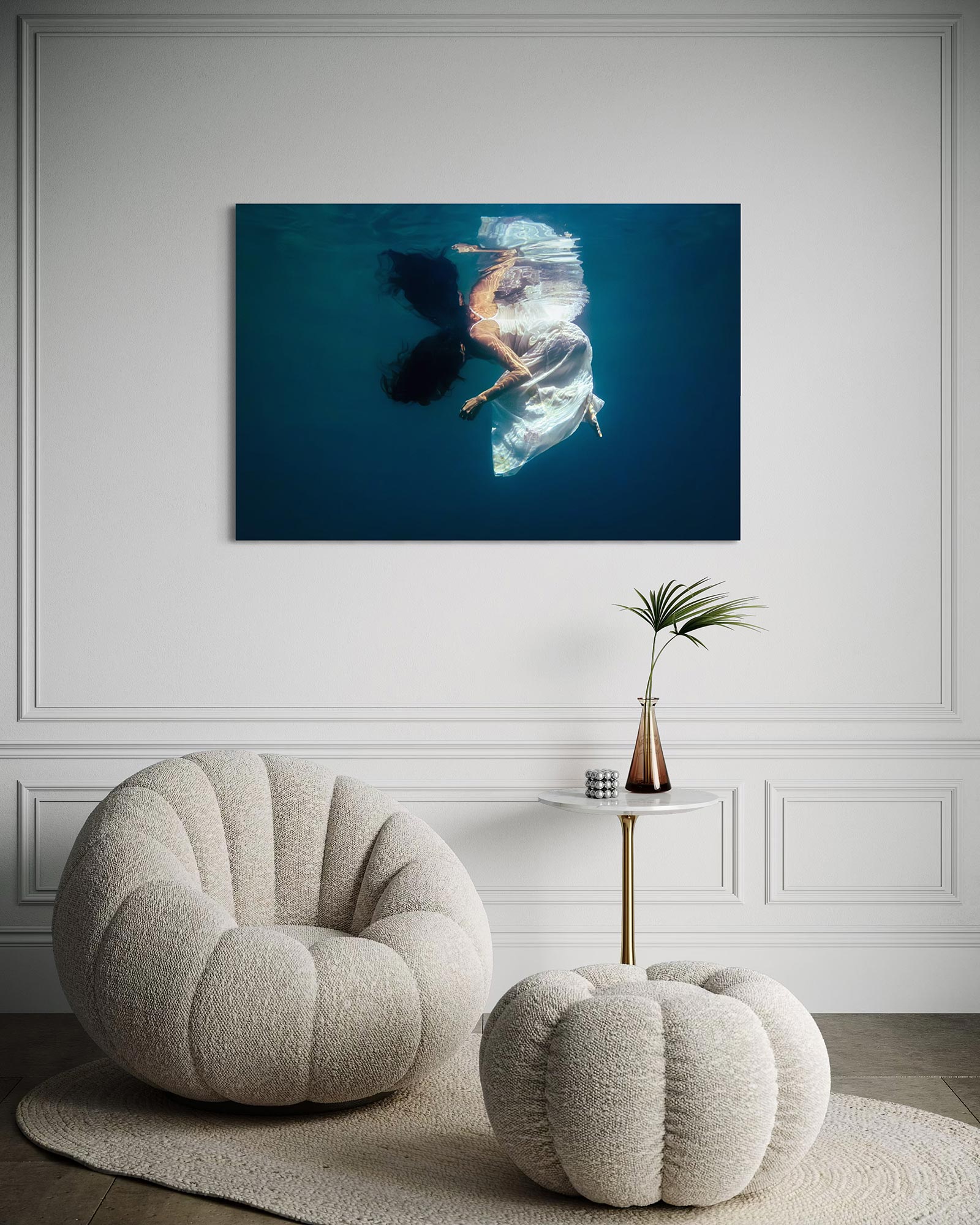 Underwater fine art photo print shown on a white wall in a modern living space above two modern armchairs.